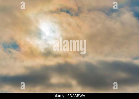 Cloudy sky, sun behind clouds. Strange view of a cloudy sky with the sun`s rays seen from behind the clouds. Cloudy sky with patches of blue and the s Stock Photo